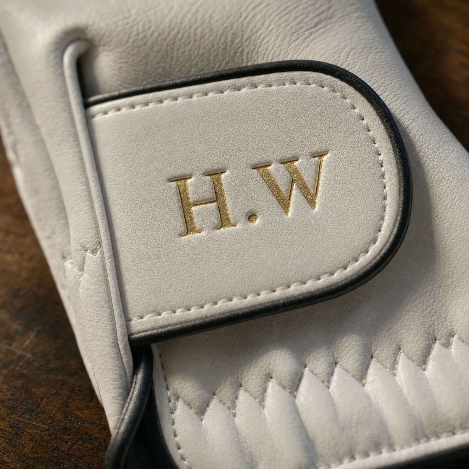 Gold foil initials hot-stamped into the cabretta closure tab, close up