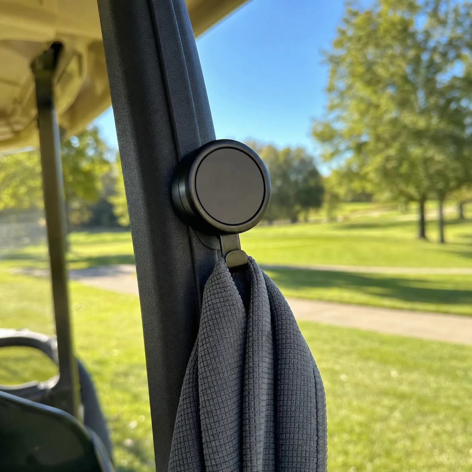 The magnetic clip holding a towel to the frame of a golf cart